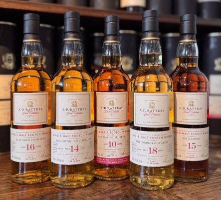 fünf Flaschen Whisky stehen auf einem Tresen, im Hintergrund Geschenkhüllen