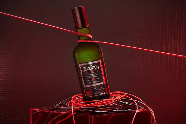 Ardbeg Vintage_Y2K 25 Jahre eine Flasche Ardbeg Vintage_Y2K 25 Jahre umschlungen von Kabeln in einem rot beleuchteten Raum