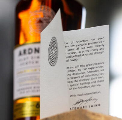Ardnahoe Chairman's Selection im Vordergrund ein Brief, im Hintergrund eine Flasche Whisky