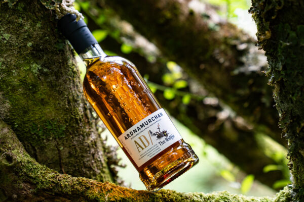 Ardnamurchan AD/ The Midgie Release 2026 eine Flasche Ardnamurchan AD/ The Midgie Release 2026 lehnt an einen Baum