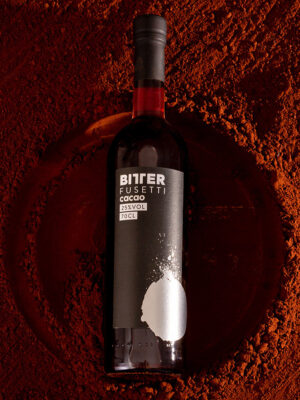 eine Flasche Bitter Fusetti Cacao liegt in Kakaopulver