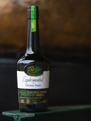 eine Flasche Christian Drouin Calvados Expérimental Planteray Clarendon Angels steht vor einer Kupferbrennblase