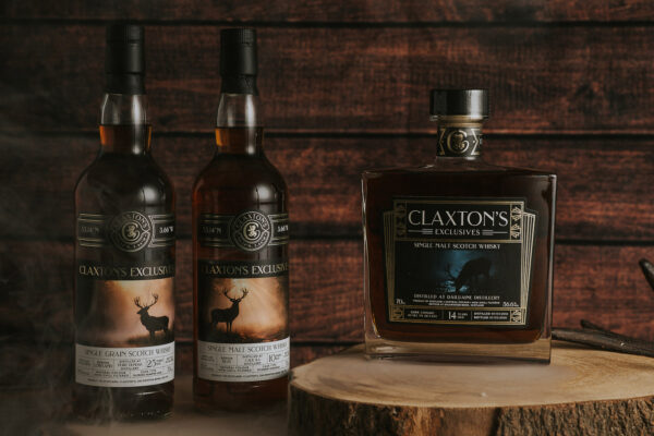 Claxton's Single Cask Bottlings drei Flaschen Whisky auf einer Baumscheibe vor einer Holzwan