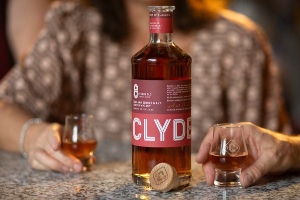 Clydeside 8 Jahre Small Batch eine Flasche Clydeside 8 Jahre Small Batch umgeben von zwei in Händen gehaltenen Gläsern