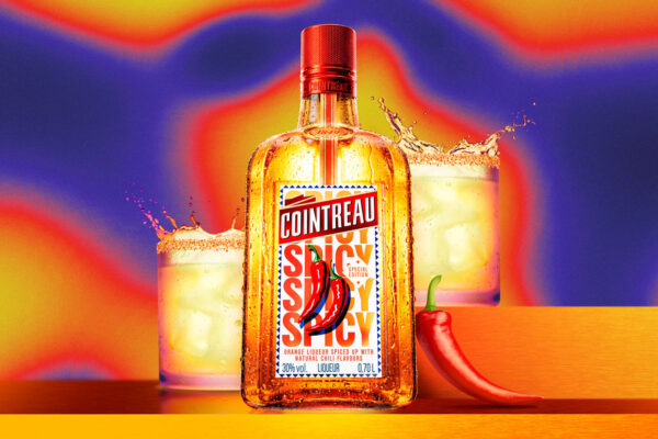 eine leuchtende Flasche Cointreau Spicy, daneben eine Chilischote und dahinter zwei Drinks