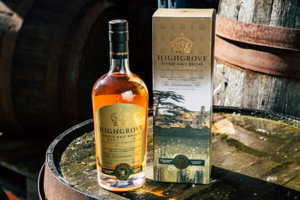 das Foto zeigt eine Flasche Cotswolds Highgrove Evergreen nebst Geschenkverpackung auf einem Holzfass