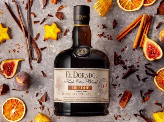 eine Flasche El Dorado High Ester Blend 2012 LBI/DHE, umgeben von Früchten und Gewürzen