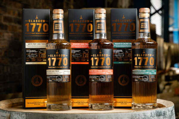drei Flaschen Whisky auf einem Holzfass