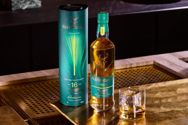 Glenfiddich 16 Jahre Aston Martin Formula One Team Limited Edition Release No. 2 eine Flasche Glenfiddich 16 Jahre Aston Martin Formula One Team Limited Edition Release No. 2 samt Verpackung und Glas auf einem Küchentresen