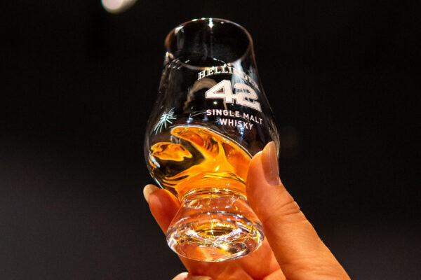 eine Glas Whisky wird in die Höhe gehalten