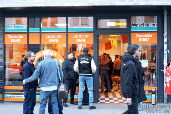 das Foto zeigt Menschen vor und in einem Waschsalon