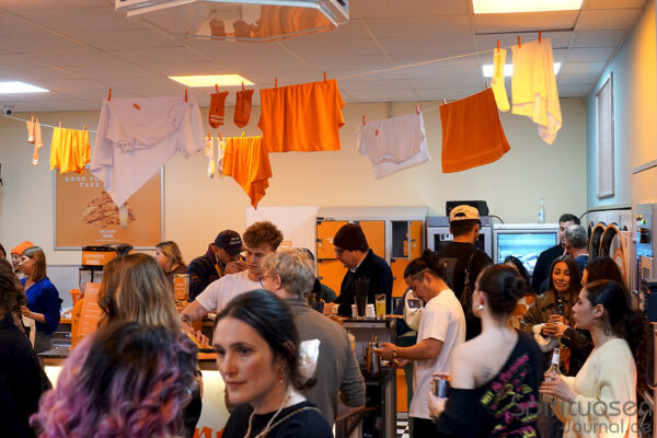 das Foto zeigt Menschen in einem Waschsalon. Mehrere haben Drinks in den Händen