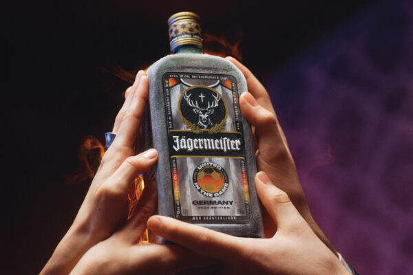 das Foto zeigt eine Flasche Jägermeister „United in the Game“ Germany 2026 Edition, hochgehoben von mehreren Händen