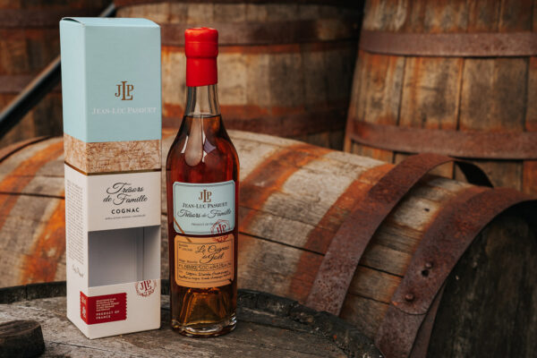 Cognac Jean-Luc Pasquet Le Cognac de Joël L.88/82 eine Flasche Cognac Jean-Luc Pasquet Le Cognac de Joël L.88/82 samt Geschenkverpackung auf einem Holzfass, im Hintergrund weitere Holzfässer