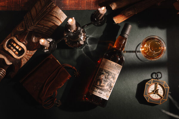 Journal des Kirsch French West Indies Rhum 2019/2026 eine Flasche Journal des Kirsch French West Indies Rhum 2019/2026 liegt auf einem Tisch, drum herum ein Kompass, ein Glas, ein Buch, ein Kerzenständer