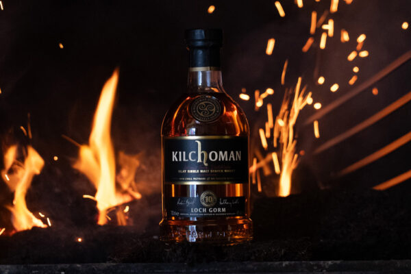 eine Flasche Kilchoman Loch Gorm 2026 Edition vor einem Feuer