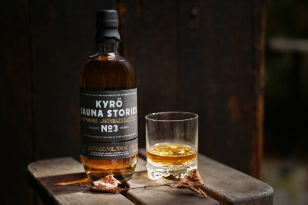 Kyrö Sauna Stories No. 3 eine Flasche Kyrö Sauna Stories No. 3 nebst Glas auf einem Hocker