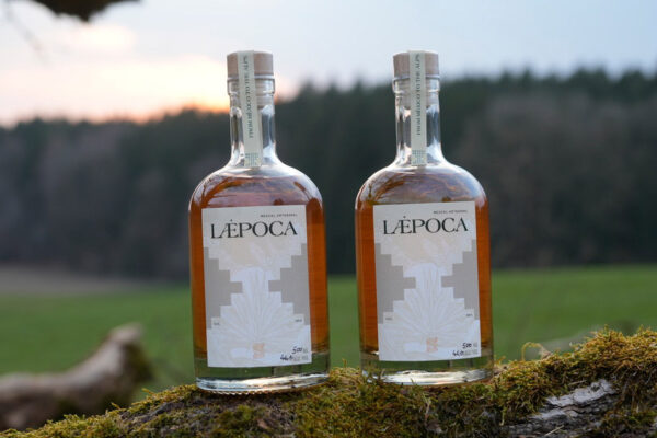 zwei Flaschen Læpoca Reposado Edition Allgäu auf einem Ast im Grünen