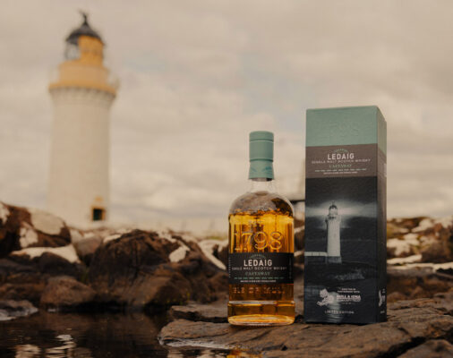 Ledaig Castaway eine Flasche Ledaig Castaway nebst Geschenkverpackung auf einer felsigen Küste. Im Hintergrund ein Leuchtturm