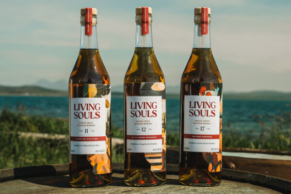 Living Souls drei Flaschen Whisky stehen auf einem Holzfass in Küstennähe