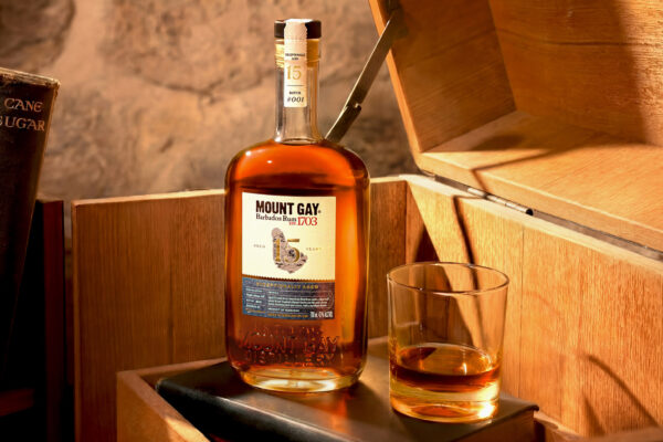 eine Flasche Mount Gay Exceptionally Aged 15 Jahre nebst eines Glases auf einem Holzpodest