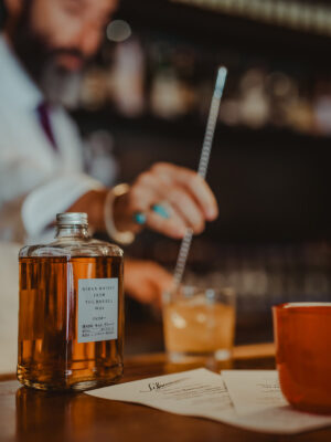 Nikka Perfect Serve 2026 das Foto zeigt einen Bartresen, vorne eine Flasche Whisky, hinten einen Barmann, der einen Drink rührt