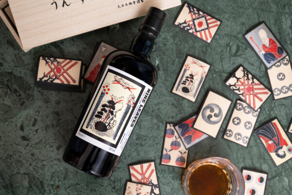 Nine Leaves 2020 PX Sherry Casks eine Flasche Nine Leaves 2020 PX Sherry Casks liegt auf einem Tisch. Um sie herum Karten des Spiels Unsun Karuta