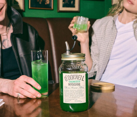 ein Einmachglas O'Donnell Moonshine Waldmeister auf einem Tisch in einer Bar. Zwei Menschen genießen den Likör