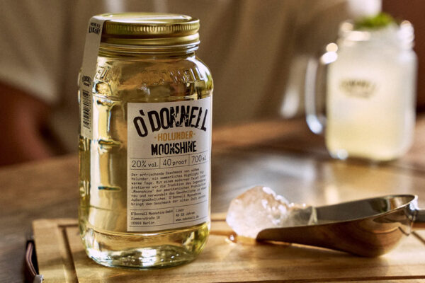 O'Donnell Moonshine Holunder ein Einmachglas O'Donnell Moonshine Holunder steht auf einem Holzbrett. Daneben ein Eiswürfel