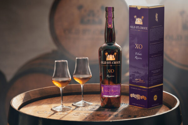 Old St. Croix XO Tribute Reserve eine Flasche Old St. Croix XO Tribute Reserve samt Geschenkverpackung und zweier Gläser steht auf einem Holzfass in einem Fasskeller
