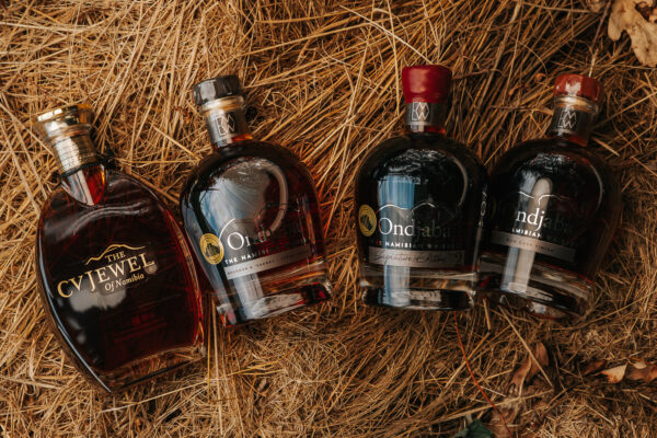 eine Flasche Brandy und drei Flaschen Whisky liegen im Stroh