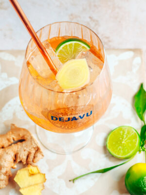 Déjà-Vu Spice Root der Drink "Déjà-Vu Spice Root", umgeben von Limetten und Ingwerwurzeln