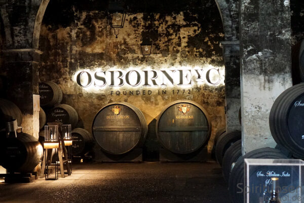 in einer Bodega, Fässer und an der Wand ein beleuchteter Osborne Schriftzug
