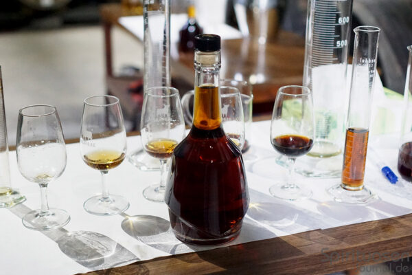 eine Flasche Brandy samt Gläser und Reagenzgläser auf einem Tisch