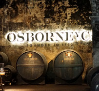 Exklusiv: Blending Session mit Osbornes Master Blender Marcos Alguacil das Foto zeigt das Innere eines Fasslagers, an der Wand eine beleuchtete Reklame