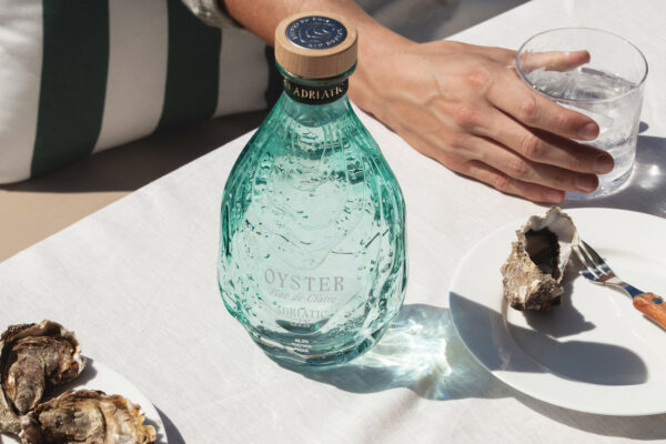 Oyster Adriatic Gin eine Flasche Oyster Adriatic Gin nebst Tellern mit Austern und einem Drink auf einem Tisch