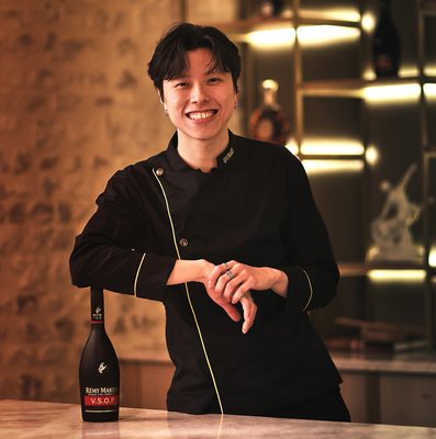 Ken Chan ein Mensch, angelehnt an eine Flasche Rémy Martin VSOP, steht in einer Bar