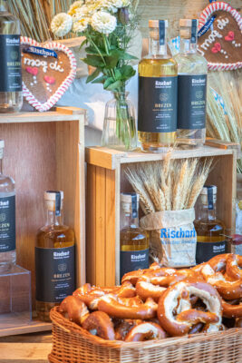 Rischart Brezn Gin und Rischart Brezn Salted Caramel Liqueur mehrere Flaschen und ein Korb Brezeln stehen im Schaufenster eines Geschäfts