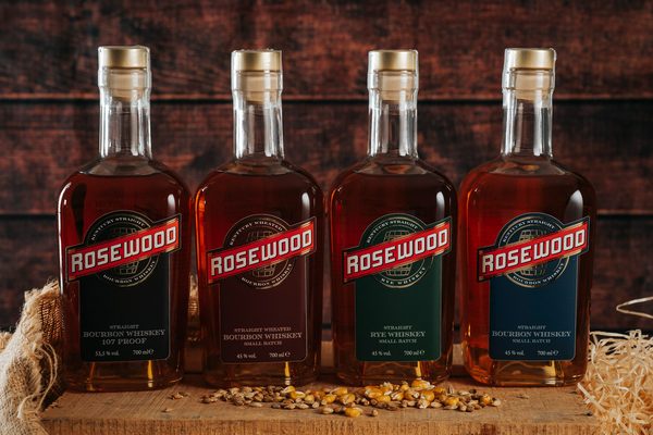 Rosewood Whiskey vier Flaschen Whiskey stehen auf einem Holzbrett