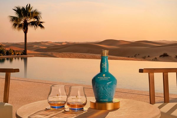 Royal Salute 21 Jahre The Desert Jewel Polo Edition eine Flasche Royal Salute 21 Jahre The Desert Jewel Polo Edition nebst Gläsern auf einem Tisch vor einem Pool in der Wüste