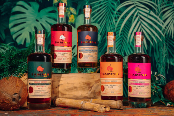 Sampan Rhum Cellar Series das Foto zeigt fünf Flaschen Sampan Rhum umgeben von Bambus, Kokosnuss und Farnen