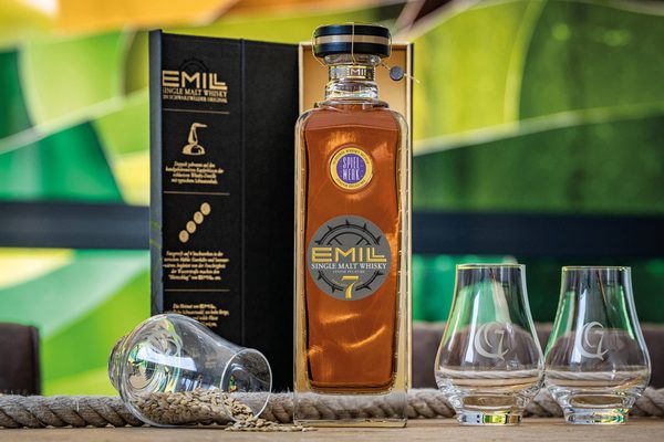 Emill Spielwerk 7 Jahre Finish Pflaume eine Flasche Emill Spielwerk 7 Jahre Finish Pflaume in einer Geschenkschatuelle, daneben Gläser, Gerste und ein Seil