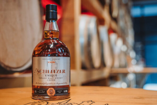 Schlitzer Unique Single Malt -Cream- eine Flasche Schlitzer Unique Single Malt -Cream- steht auf einem Holztisch in einem Fasslager