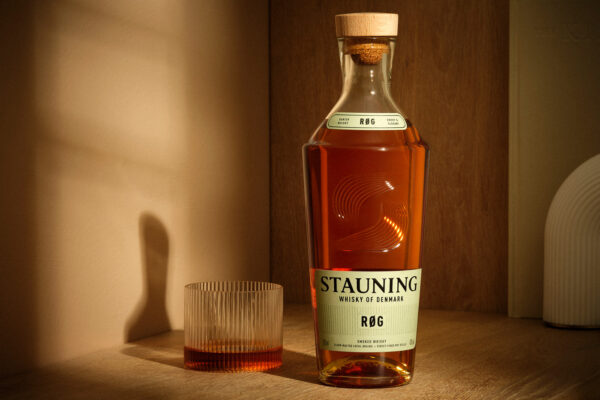 Stauning RØG eine Flasche Stauning RØG nebst Glas in einem Holzregal