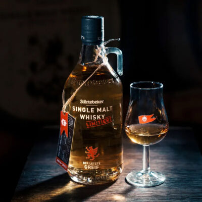 Störtebeker Single Malt „Der letzte Greif“ das Foto zeigt eine Flasche Whisky nebst Glas in einem dunklen Raum