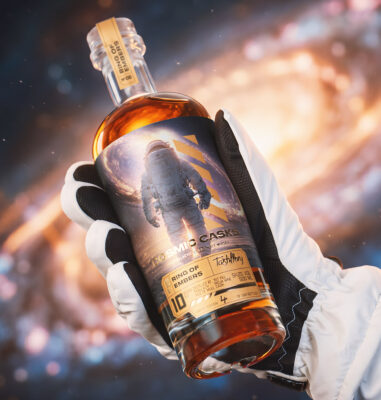 eine Flasche Cosmic Casks 06: Ring of Embers, gehalten von einer Hand in einem Handschuh