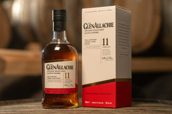 The GlenAllachie 11 Jahre Palo Cortado Sherry Finish eine Flasche The GlenAllachie 11 Jahre Palo Cortado Sherry Finish nebst Geschenkverpackung, im Hintergrund Holzfässer