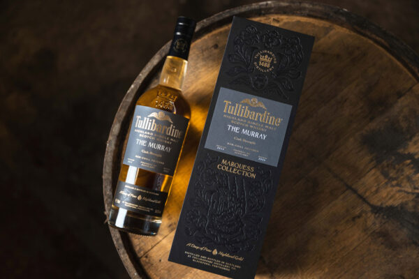 eine Flasche Tullibardine The Murray 2013 Cask Strength nebst Geschenkhülle, liegend auf einem Holzfass