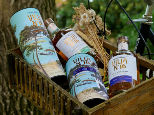 zwei Flaschen Villa N°16 Whisky samt Geschenkhüllen in einem hölzernen Fahrradkorb