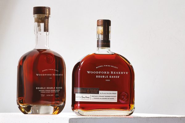 eine Flasche Woodford Reserve Double Double Oaked und eine Flasche Woodford Reserve Double Oaked auf einem weißen Podest in einem weißen Raum